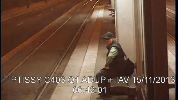 Eine Person mit Kappe und Tasche sitzt auf einer Treppe in der Nähe einer Straße.