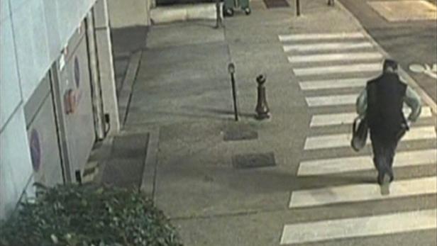 Ein Mann überquert einen Zebrastreifen mit einer Tasche in der Hand.