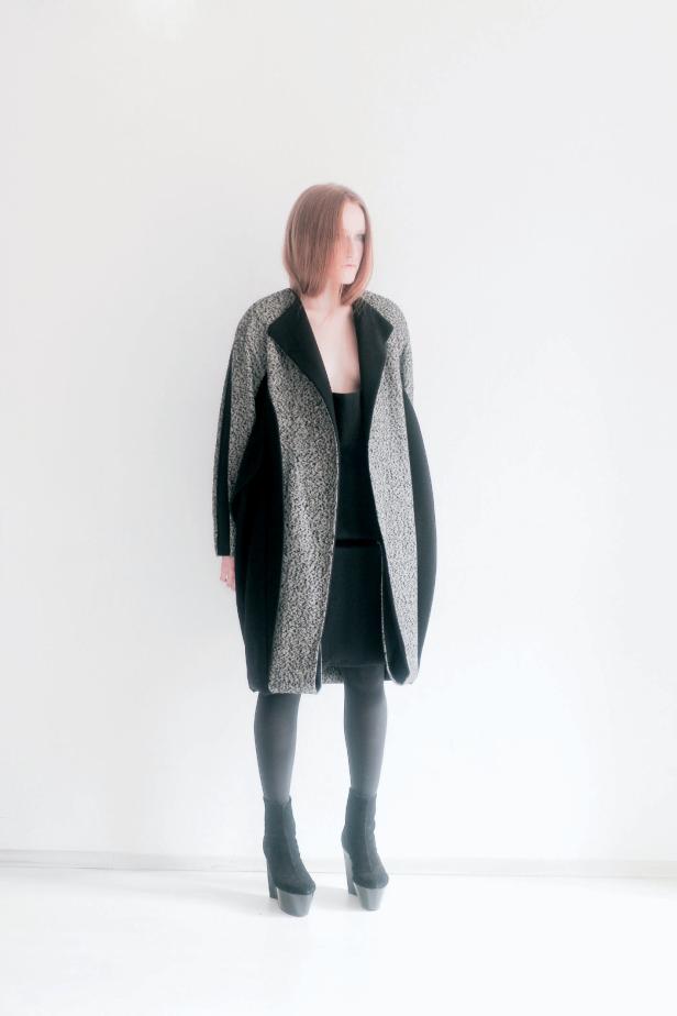 Eine Frau mit rotem Haar trägt einen Mantel und schwarze Stiefel.