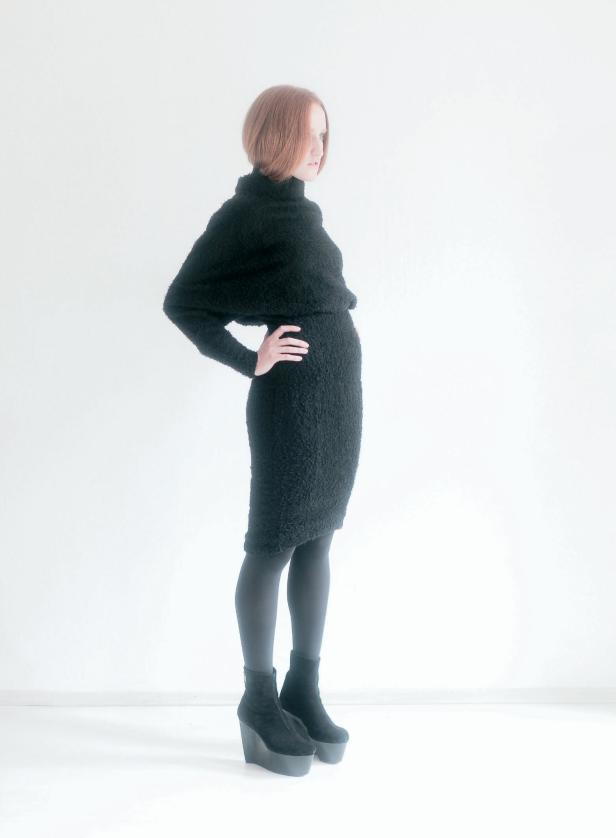 Eine Frau mit rotem Haar trägt ein schwarzes Kleid und Stiefel mit Plateausohle.