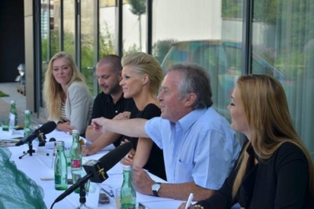 Eine Gruppe von Menschen sitzt an einem Tisch mit Mikrofonen und Wasserflaschen.