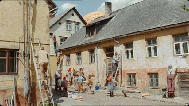 Eine Gruppe von Menschen renoviert gemeinsam die Fassade eines alten Hauses.
