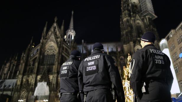 Drei Polizisten stehen nachts vor dem Kölner Dom.