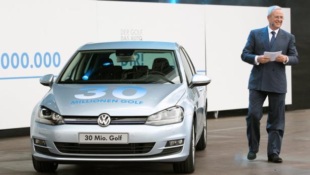 Ein Mann im Anzug steht neben einem hellblauen VW Golf „30 Millionen“.