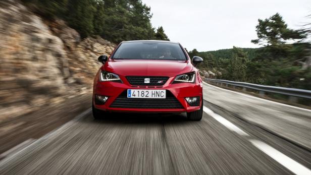 Ein roter Seat Ibiza fährt auf einer Landstraße.