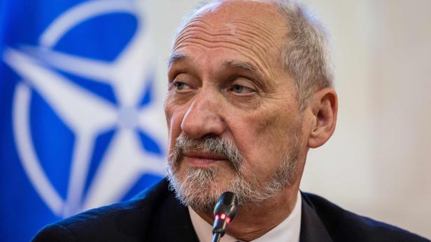 Verteidigungsminister Antoni Macierewicz Ein Mann mit Bart spricht vor einer NATO-Flagge.