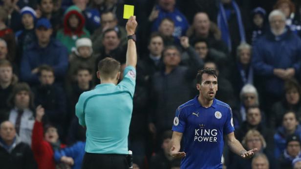 Ein Schiedsrichter zeigt einem Fußballspieler die gelbe Karte.