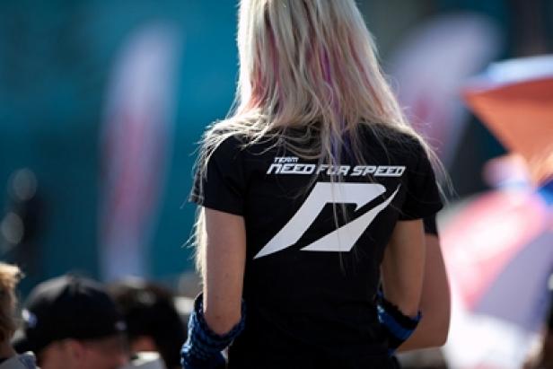 Electronic Arts -Need for Speed - Markenbotschafterin (c: ea) Eine Frau mit blonden Haaren trägt ein „Need for Speed“-T-Shirt.
