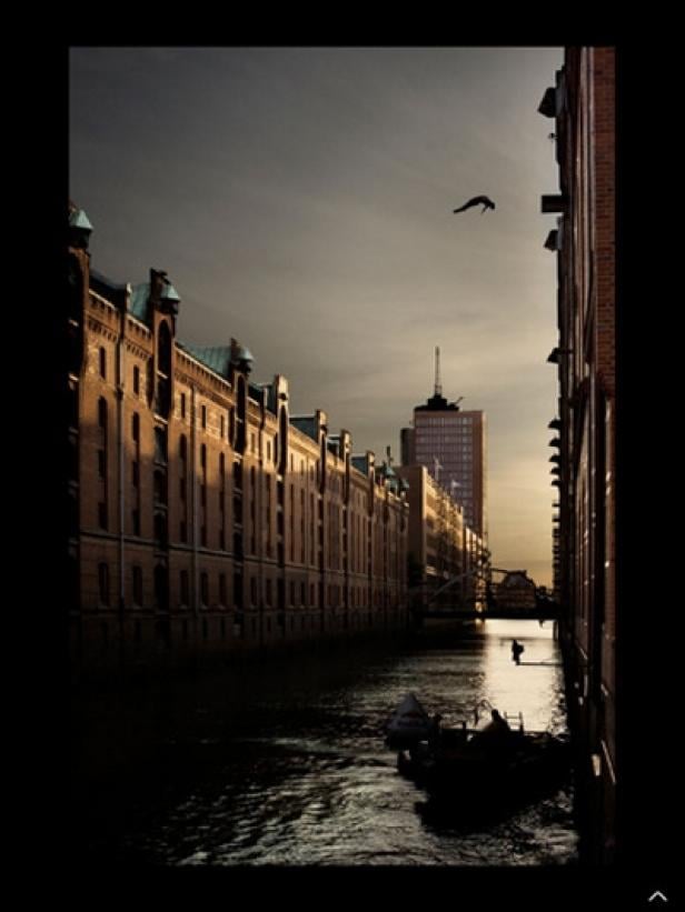 Blick auf die Speicherstadt in Hamburg mit einem Mann, der ins Wasser springt.