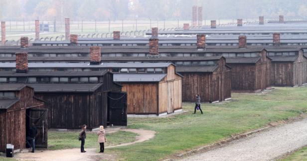 Blick auf die Baracken in Auschwitz-Birkenau mit Besuchern im Vordergrund.