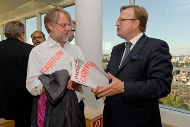 Zwei Männer unterhalten sich und halten Papiere mit der Aufschrift „Cashflow“ in der Hand.