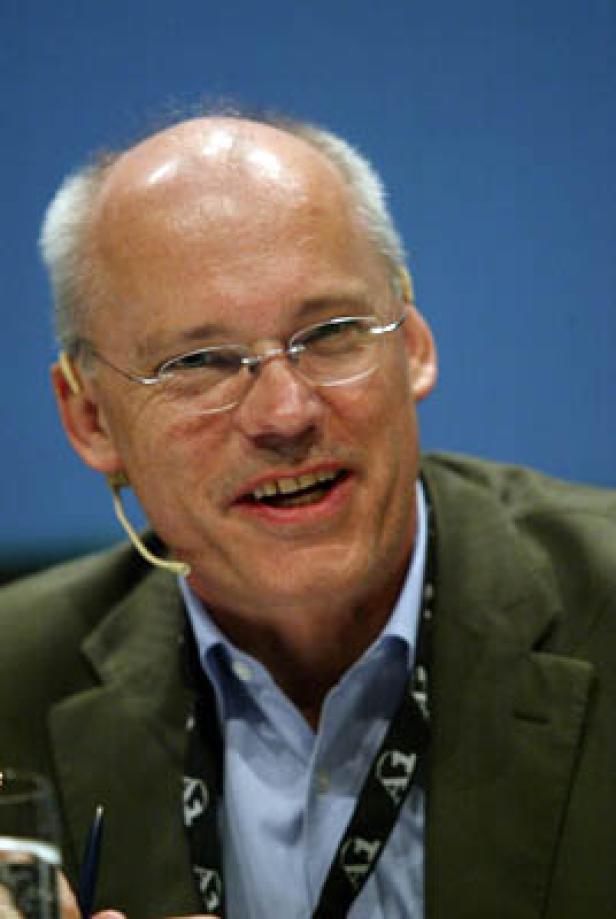 Ein Mann mit Brille und Mikrofon lächelt.