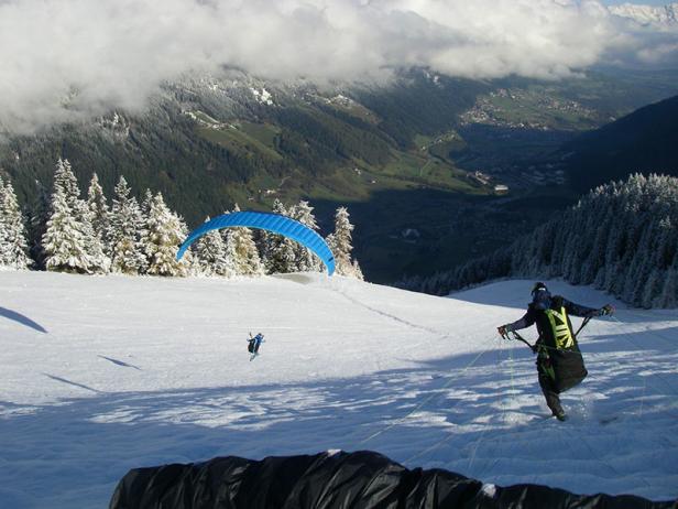 Ein Gleitschirmflieger bereitet sich auf einem schneebedeckten Hang auf den Start vor.