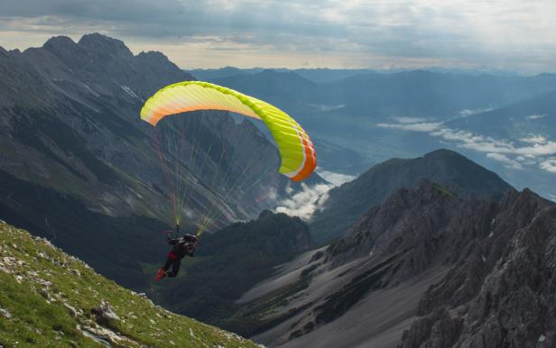 Ein Gleitschirmflieger vor einer Berglandschaft.
