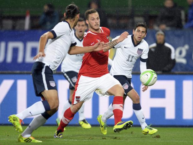 Fußballspieler der USA und Österreich kämpfen um den Ball.