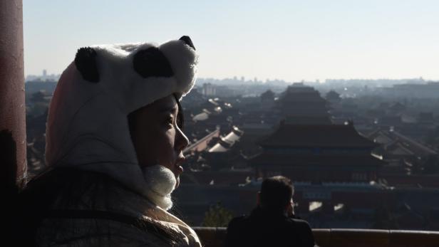 Eine Frau mit Panda-Mütze blickt auf die Verbotene Stadt in Peking.