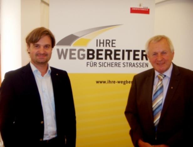 Daniel Frixeder (upart), Franz Hiesl (Landeshauptmann-Stellvertreter und Straßenbau-Referent Land Oberösterreich) (c: upart) Zwei Männer stehen vor einem Banner mit der Aufschrift „Ihre Wegbereiter für sichere Straßen“.