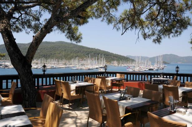 Ein Restaurant mit Blick auf einen Yachthafen mit vielen Segelbooten.