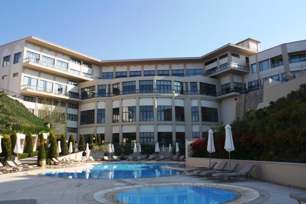 Ein Hotel mit Swimmingpool und Liegestühlen an einem sonnigen Tag.