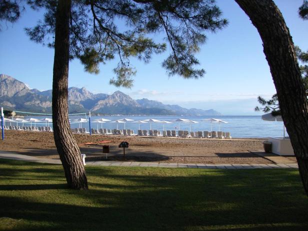 Ein Strand mit Liegestühlen und Sonnenschirmen vor einer Bergkulisse.