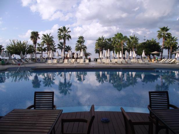 Ein Schwimmbad mit Liegestühlen und Sonnenschirmen unter Palmen.