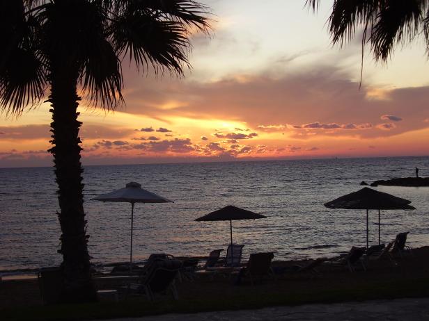 Ein Strand mit Sonnenschirmen und Liegestühlen bei Sonnenuntergang.