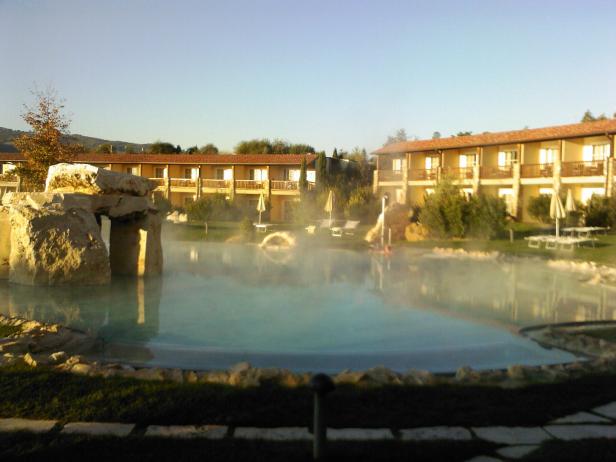 Ein Thermalbad mit Liegestühlen vor einem Hotelgebäude.