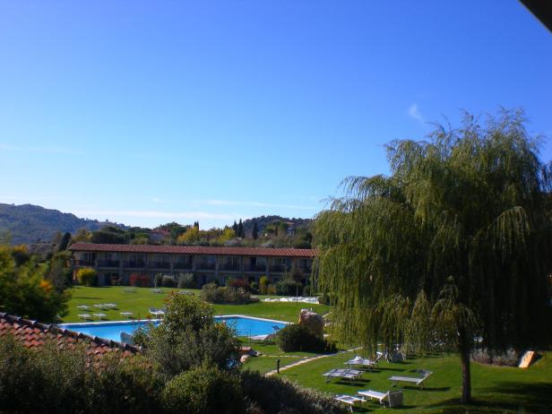 Ein Hotel mit Pool und Liegestühlen auf einer grünen Wiese.