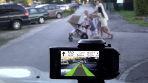 Wikitude Drive/ab November im Android-Market (c: mobilizy) Eine Familie überquert eine Straße, aufgenommen mit einer Dashcam.