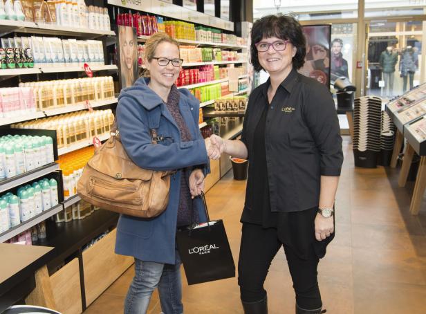 Eine Kundin schüttelt einer Verkäuferin in einem L'Oréal-Geschäft die Hand.