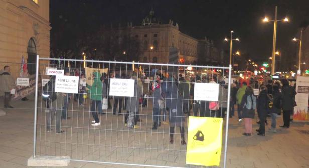 Eine Demonstration gegen Zäune vor einem Gebäude in der Nacht.