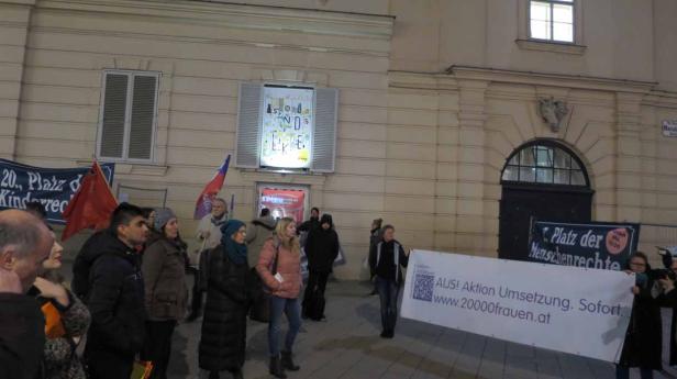 Eine Demonstration mit Bannern vor einem Gebäude in Wien.