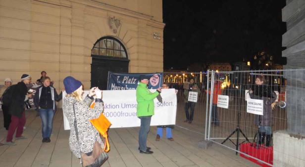 Eine abendliche Demonstration mit Transparenten und Schildern gegen Zäune.