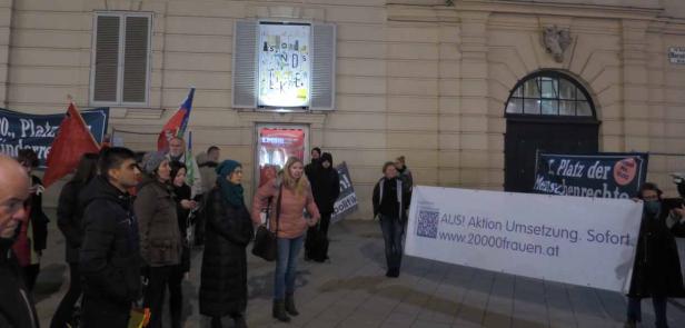 Eine Demonstration mit Transparenten und Flaggen vor einem Gebäude in Wien.