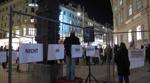 Eine Demonstration gegen Grenzen mit Schildern in einer Stadt bei Nacht.