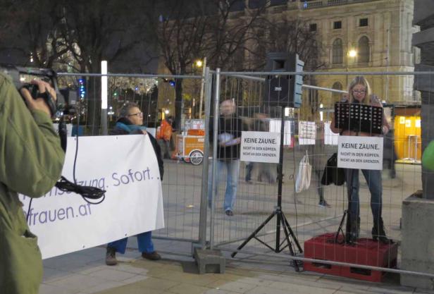 Eine Frau liest bei einer Kundgebung mit Schildern gegen Zäune und Grenzen.