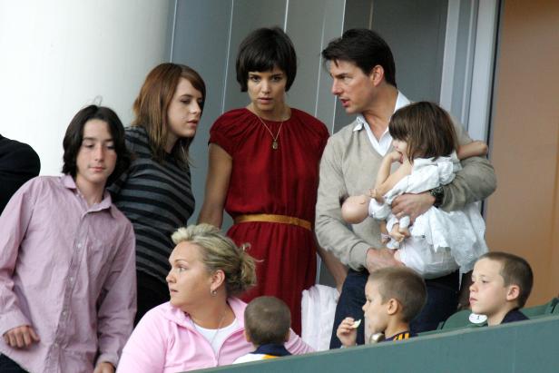 Tom Curise Tom Cruise hält seine Tochter Suri im Arm, daneben Katie Holmes und weitere Personen.