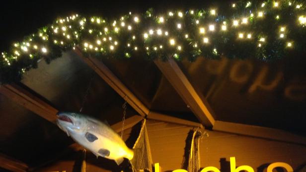 Ein Fisch hängt an einer Kette unter einer Lichterkette.