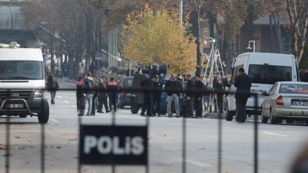 Polizisten stehen auf einer Straße mit einem gepanzerten Fahrzeug und mehreren Lieferwagen.