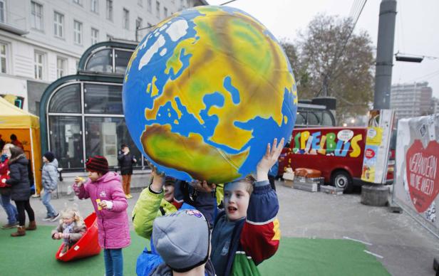 Eine Gruppe Kinder hält einen großen Globus in die Höhe.