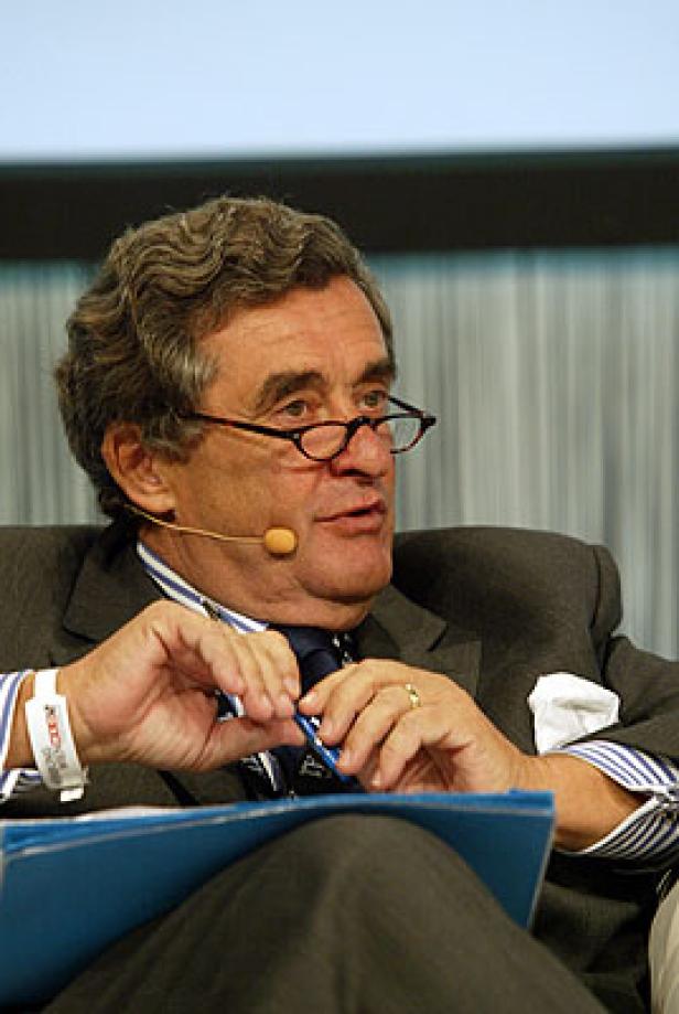 Ein älterer Mann mit Brille und Anzug spricht bei einer Konferenz.
