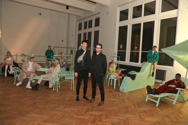 In einem Raum posieren Models und zwei Männer vor mintgrünen Möbeln.