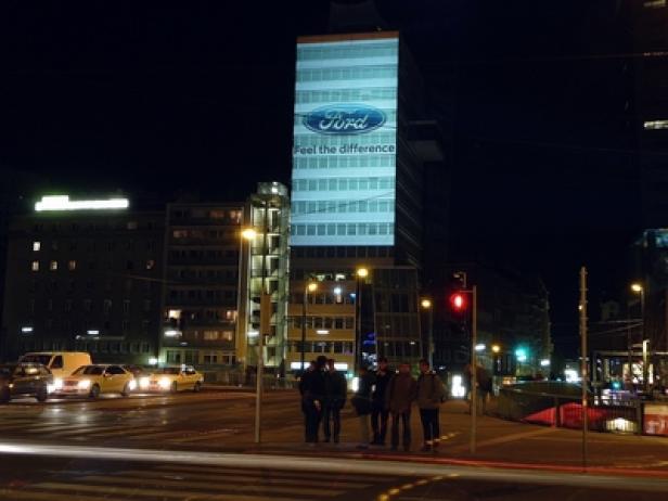 Ein Ford-Logo wird nachts auf ein hohes Gebäude projiziert.