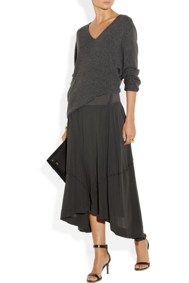 Eine Frau trägt einen grauen Pullover, einen Rock und Sandalen mit Absatz.