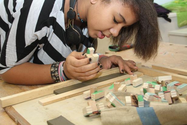 Eine junge Frau bastelt mit Holzklötzen, die mit Buchstaben versehen sind.