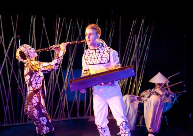 Zwei Musiker in Kostümen treten auf einer Bühne auf, einer spielt Klarinette, der andere hält ein Tasteninstrument.