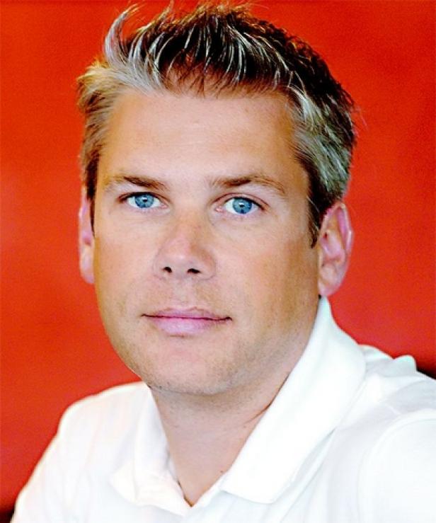 Porträt eines Mannes mit blonden und grauen Haaren vor einem roten Hintergrund.