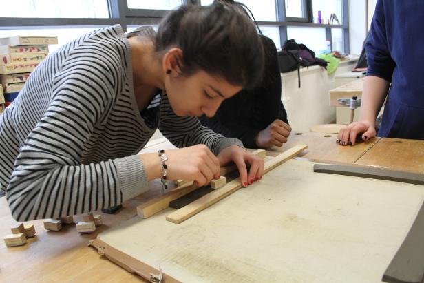 Eine Frau arbeitet mit Holzstücken an einem Tisch.