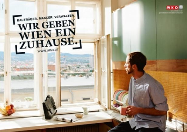 Ein Mann blickt aus dem Fenster mit Blick auf Wien und hält eine Tasse in der Hand.