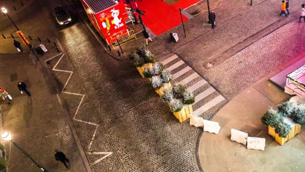 Blick von oben auf eine abendliche Stadtstraße mit Weihnachtsdekoration und Passanten.